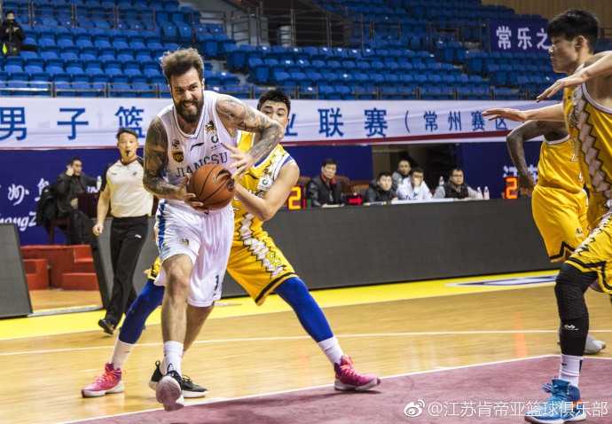 面对广厦多人包夹，肯帝亚球员奋力跃起试图传球，眼神中透露出不甘与坚韧，场边球迷纷纷起立注视