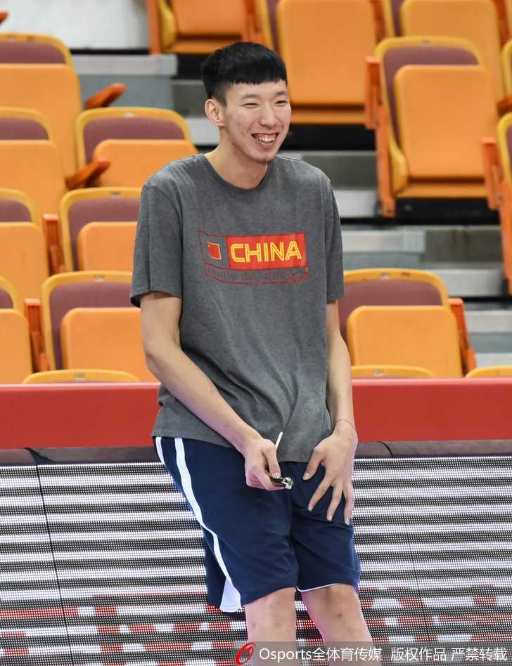 周琦身披红色战袍，在训练场上轻松运球，眼神中透露出从NBA夏季联赛归来后的自信与从容。