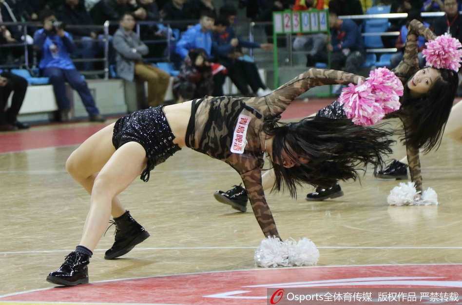 镜头特写捕捉到一位笑容灿烂的篮球宝贝，她身姿挺拔，眼神中充满了对主队胜利的坚定信念