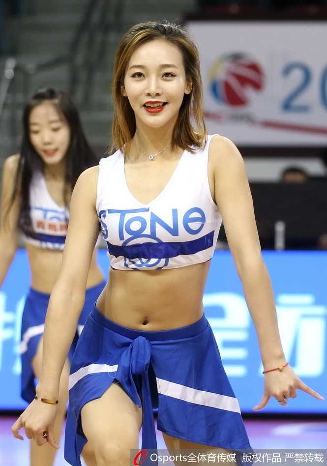 一位篮球宝贝背对镜头，却回眸一笑，高扎的马尾辫和精致的侧颜在聚光灯下勾勒出迷人的轮廓，展现出篮球宝贝自信而迷人的风采。