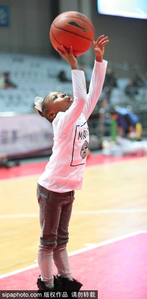 小女儿已经有些困倦，趴在爸爸肩头揉着眼睛，手里还紧紧攥着那个陪她玩了整晚的小篮球，画面安静而美好。