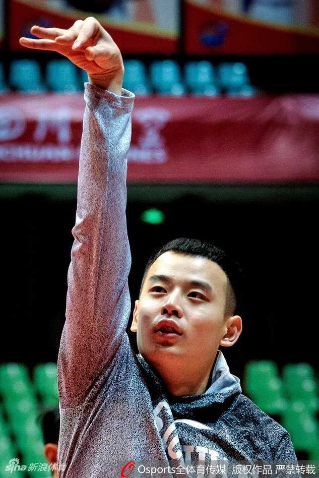 主帅在训练场边面带笑容为球员讲解战术，身后是认真聆听的队员们