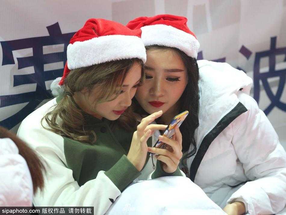 比赛间隙，两位篮球宝贝凑在一起看着手机屏幕，其中一位惊讶地捂嘴，仿佛看到了什么有趣的内容，可爱的表情与场上严肃的拼抢形成鲜明对比。