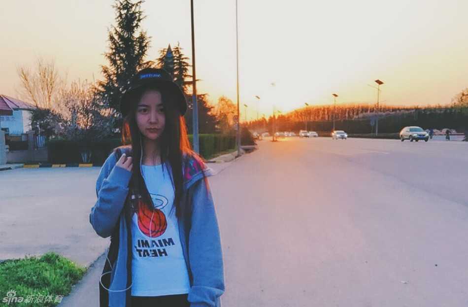 夕阳的余晖洒满空荡的球场，身穿23号球衣的女孩凝望着高高的篮筐，她的身影被拉长，眼神里写满了对扣篮的渴望与坚定。