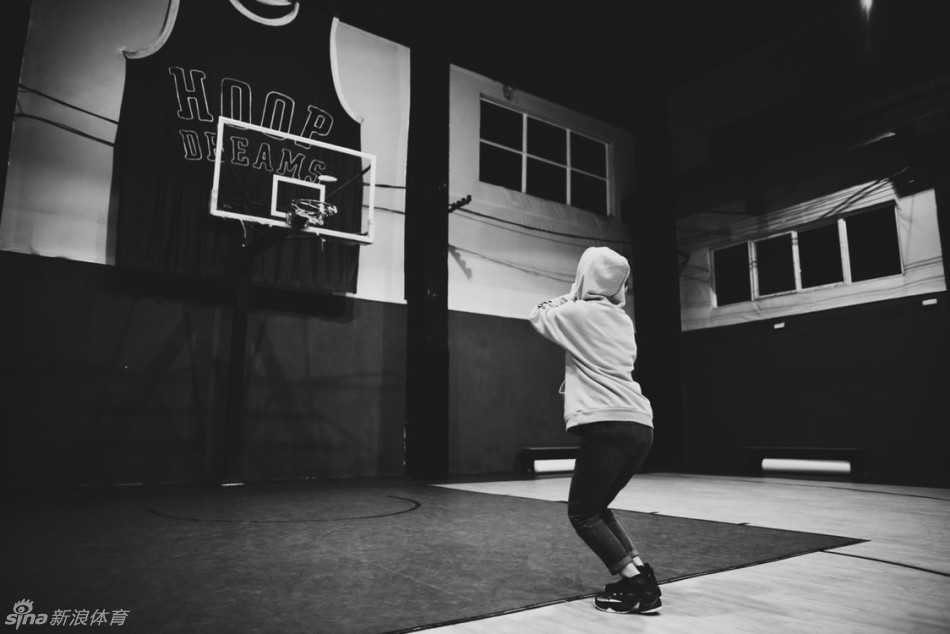 女孩在空中奋力一跃，身体舒展到极致，手中的篮球高高举起，正努力向着篮筐的方向送去。夕阳在她身后形成一道剪影，画面充满动感与力量。