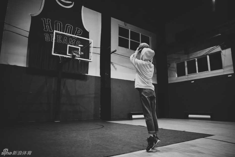 女孩双脚分开，膝盖微曲，认真模仿着偶像的投篮手型。她高高举起篮球，目光聚焦在篮筐的后沿，全身肌肉绷紧，准备完成一次标准的投篮练习。