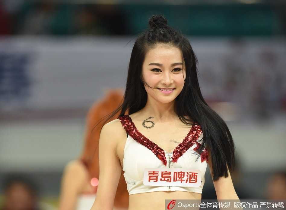 镜头拉近，领舞的篮球宝贝露出自信迷人的微笑，她手中的花球随着动感的节拍飞舞，眼神中闪烁着与场上球员同样专注的光芒。