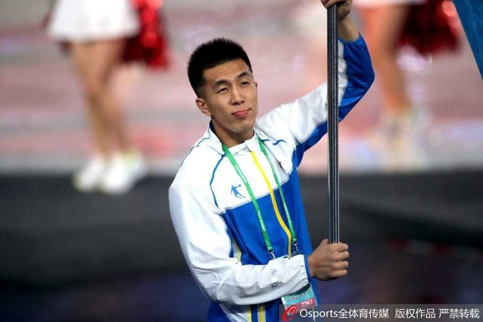 开幕式的灯光映照在郭艾伦脸上，他紧握旗杆，展现出新时代运动员的风采。