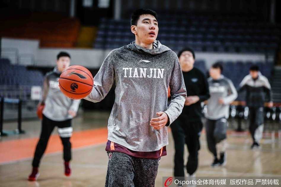 队员们在地板上认真进行拉伸训练，肌肉线条分明，体能教练在一旁细心指导，确保每个动作都发挥最大效果。