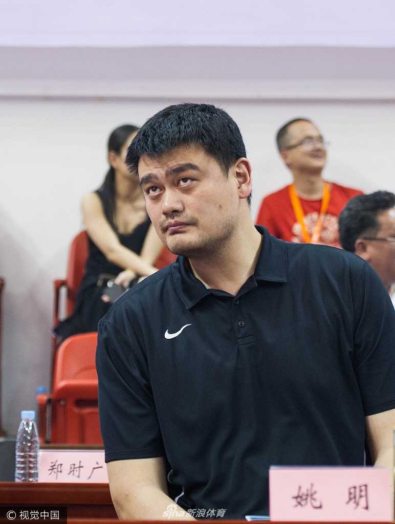 怀集体育馆内灯光璀璨，热情的观众们挥舞着手中的充气棒，目光一致投向场边正在鼓掌的姚明，现场气氛热烈非凡，仿佛一个盛大的节日庆典。