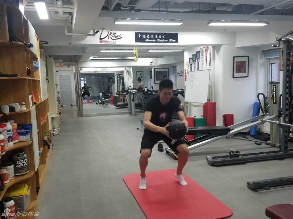 孙悦在康复师的辅助下进行平衡训练，单脚站立时表情专注而吃力，核心收紧，汗水已经浸湿了他的训练背心。