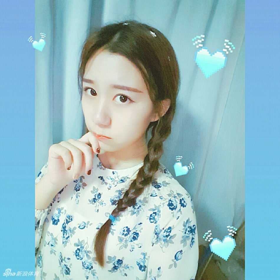 @_yoonxi身穿炫舞团专属亮色表演服，对着镜头俏皮地比出胜利手势，身后是模糊的排练场景，凸显了她活泼开朗的性格。