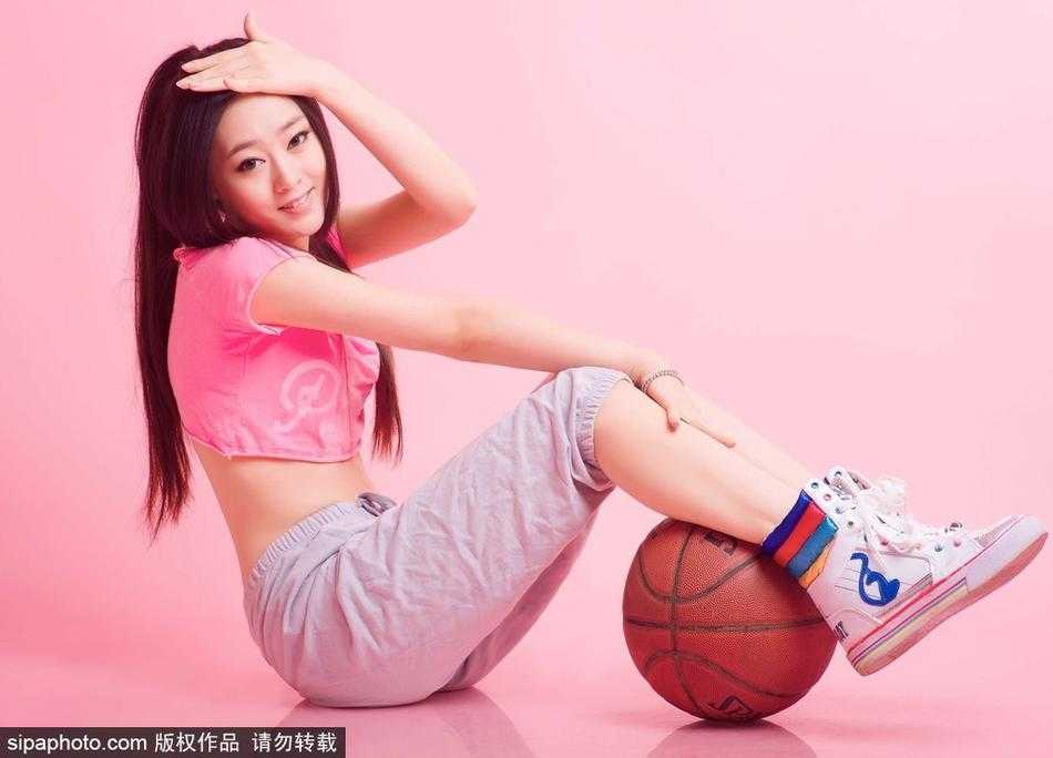 李昕瑶穿着宽松的运动背心，在篮下轻盈跃起，发丝随风飞扬，脸上洋溢着进球后灿烂又带点羞涩的笑容。