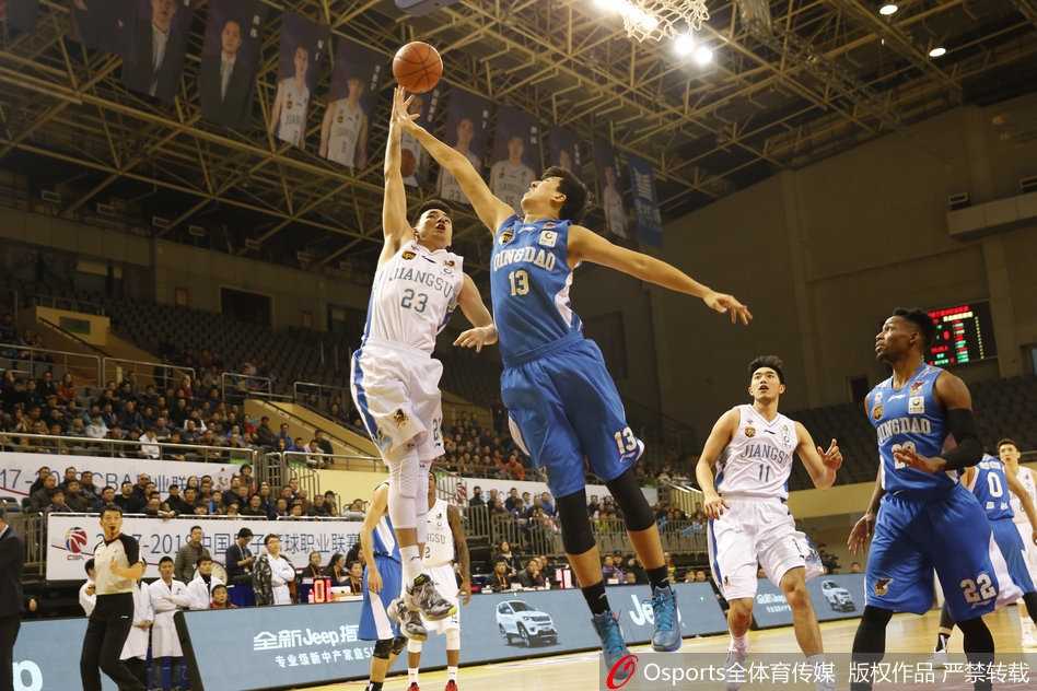 江苏队外援拉杜利察在青岛队员的严密包夹下依然高举高打，他肌肉紧绷，奋力将球放入篮筐，展现了内线支柱的强硬。