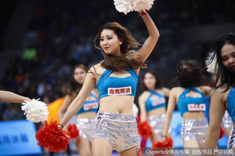 姑娘们在表演中做出高难度的托举动作，展现出力与美的结合，背景的观众席虚化成一片光点，焦点全在她们惊艳的舞姿上。