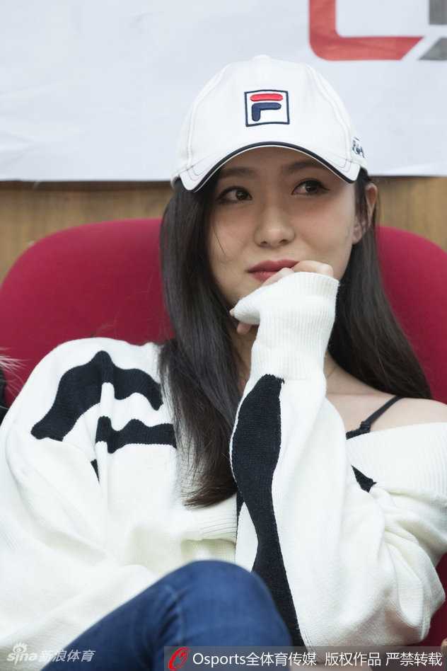 这位长发披肩的美女球迷身着一袭简约的白色外套，宛如冬日里的一抹暖阳。她安静地坐在篮架后方，眼神专注地凝视着赛场，精致的侧颜和微微上扬的嘴角，仿佛在期待着一场属于广厦的胜利狂欢。