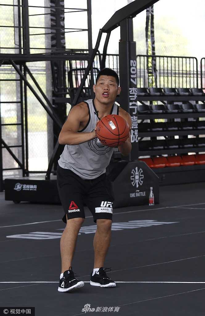 霍洛威双手运着两个篮球，脸上洋溢着搞怪的笑容，他似乎在向身边的篮球手们炫耀自己的控球技巧，轻松诙谐的氛围感染了在场的每一个人。