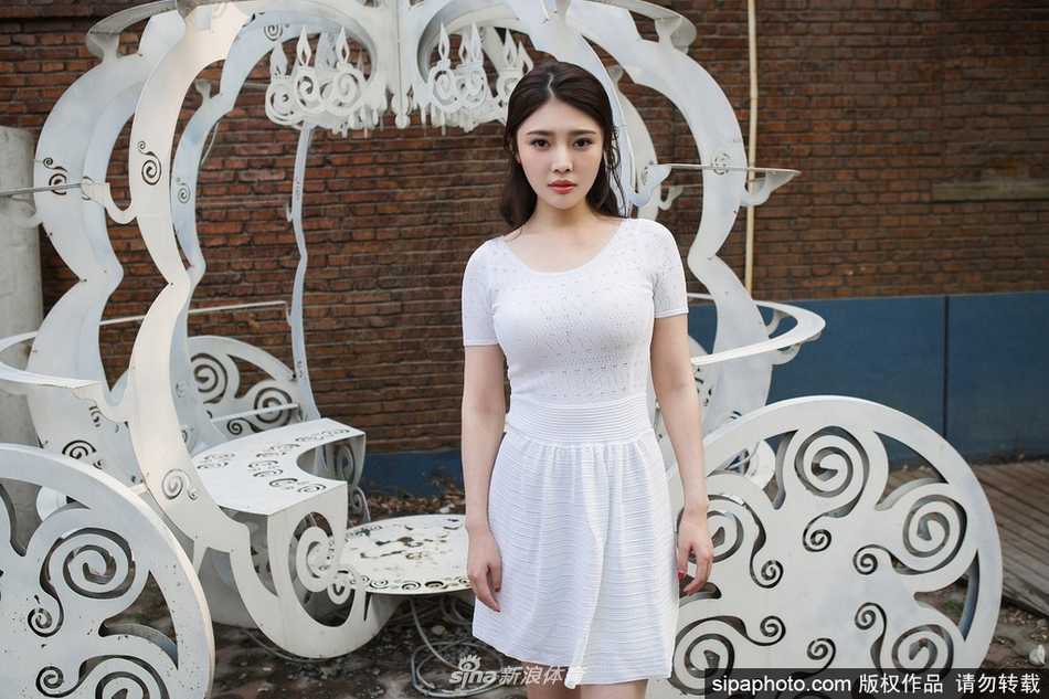 徐冬冬静立于纯色背景前，白裙的收腰设计凸显出不盈一握的纤腰，她微微垂眸，整个人散发出一种不食人间烟火的清冷仙气。