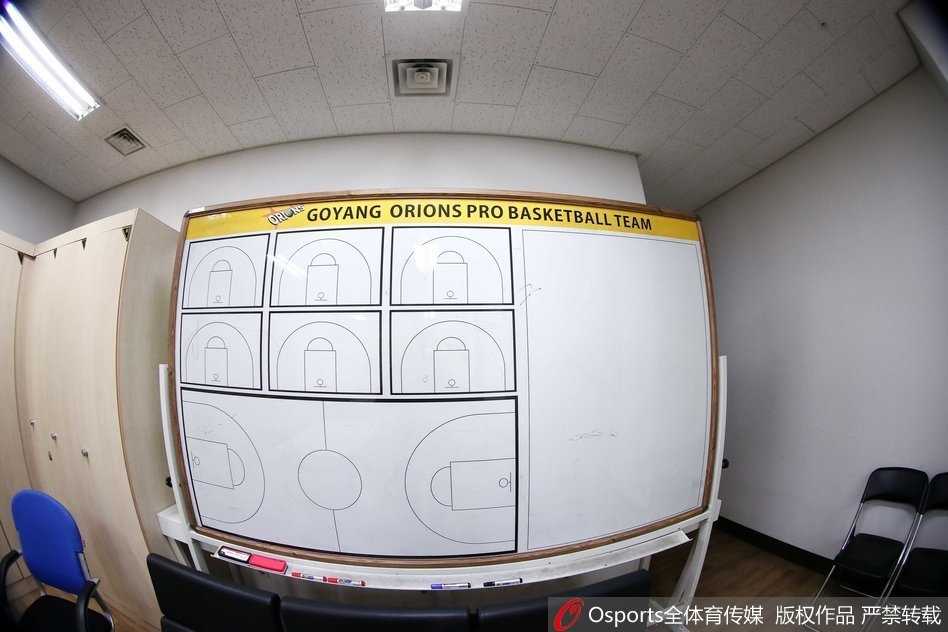 更衣室一角的皮质沙发上，一名年轻球员戴着宽大的头戴式耳机，身体随着音乐的节奏轻微晃动，紧闭的双眼仿佛隔绝了外界的一切喧嚣，沉浸在自己的内心世界里。