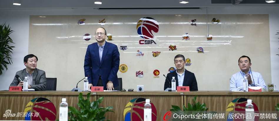 竞赛总经理张雄在话筒前神色严肃，手指轻点桌面，身后的大屏幕上显示着复杂的联赛数据图表，他正在向媒体详细解释裁判升降级制度的运行细则。