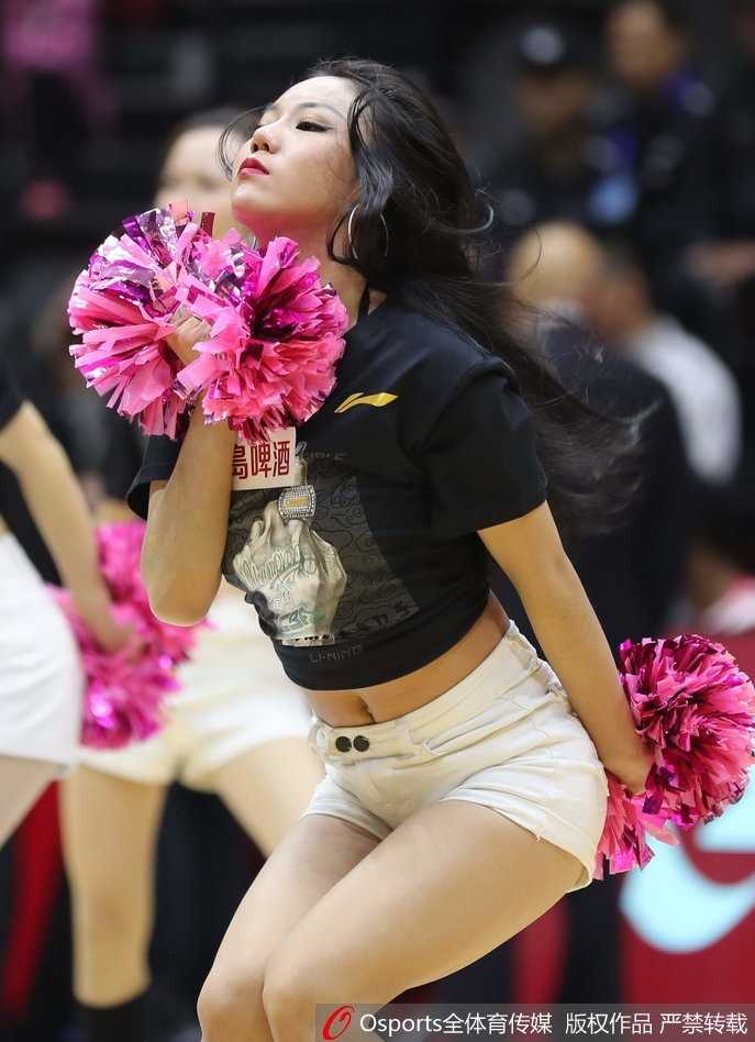 在热闹的主场环境中，一位戴着头巾的新疆美女目光如炬，静静地看着赛场，她的美丽中透着一股沉静的力量，与周围的喧嚣形成微妙对比。