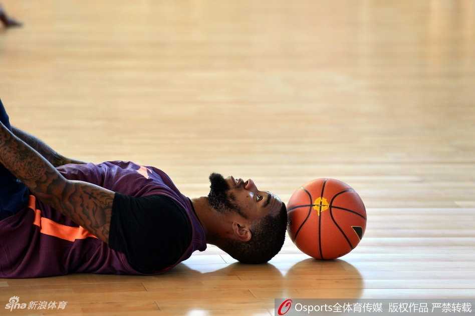 训练间隙，肖恩·左手叉腰，右手指向球场另一侧，正神情专注地与教练讨论着刚才那个回合的防守站位。