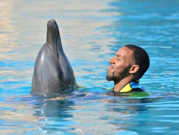 身披阳光的亚当斯在迪拜的湛蓝海水中，与优雅的海豚来了一次亲密的鼻尖对鼻尖，仿佛在交流着关于远方的秘密。
