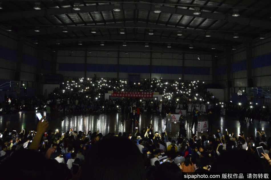 几位学生肩并肩站在一起，同时举起手机，脸上带着灿烂的笑容，手机的光芒照亮了他们的脸庞和身后的黑暗