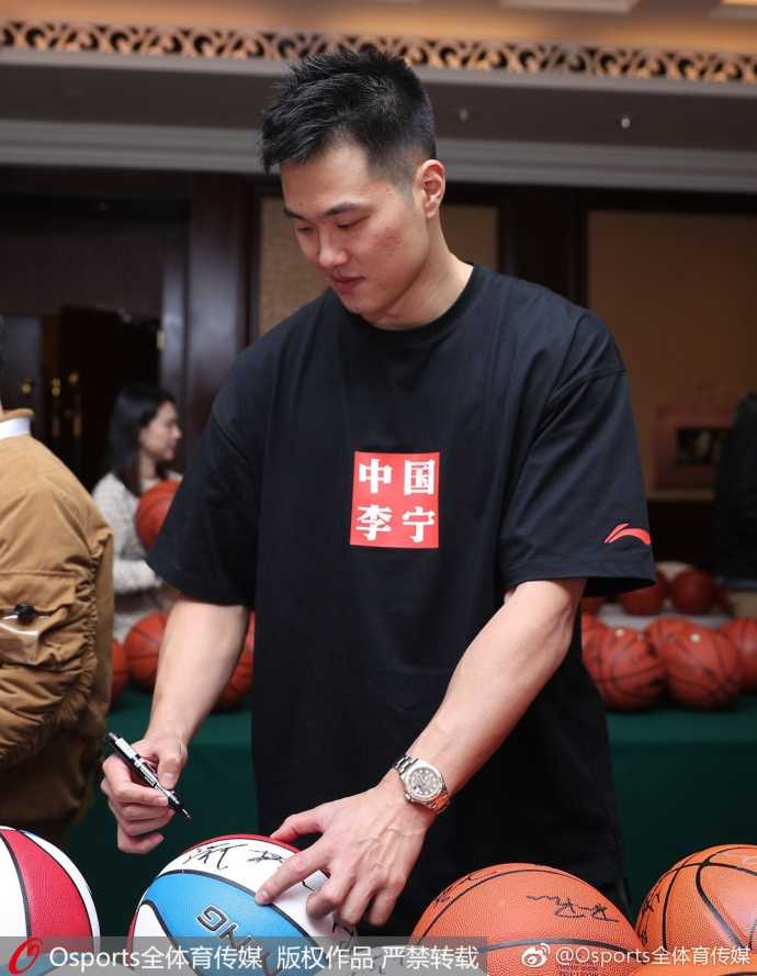 球迷高举着巨大的全明星旗帜，背景里是正在埋头签名的赵继伟和胡金秋。尽管画面聚焦于人群的狂热，但球星们依然保持着高度的亲和力，即便被包围也耐心地满足每一位球迷的愿望。