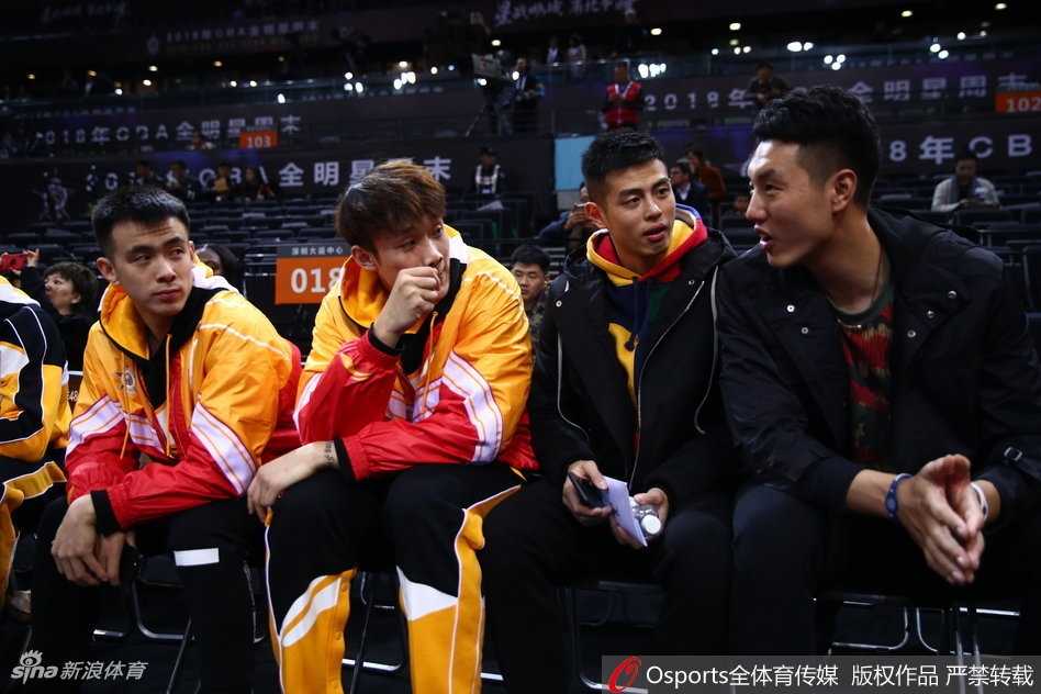 郭艾伦与方硕等北区全明星球员并肩坐在观众席上，郭艾伦手指场内，神情专注地与身旁队友交流着对比赛的看法。