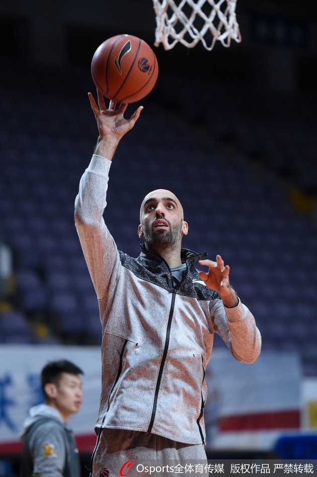 马布里在投篮训练后捡起篮球，手臂肌肉线条分明，眼神中透露出对胜利的执着与坚定