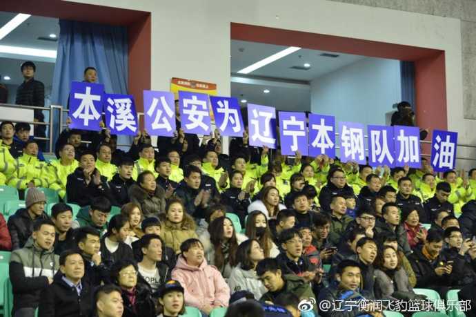 辽宁本钢队球员在赛前入场仪式中，韩德君表情轻松地与队友击掌，背景是看台上热情的本溪球迷和醒目的公益观赛团区域