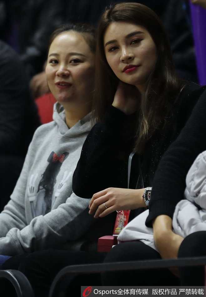 看台上的她托腮沉思，眉宇间带着一丝对场上局势的担忧，粉色的衣着让她在人群中格外亮眼。