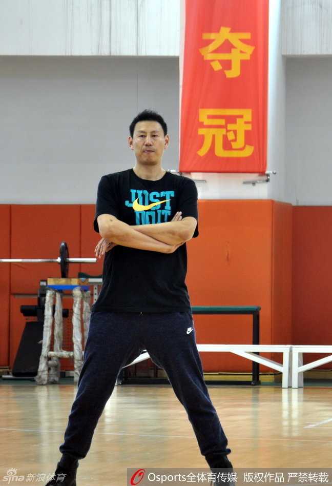 铁帅李楠双手叉腰站在训练场中央，目光如炬，霸气十足的站姿彰显出他对球队纪律的严格要求和对胜利的无限渴望。