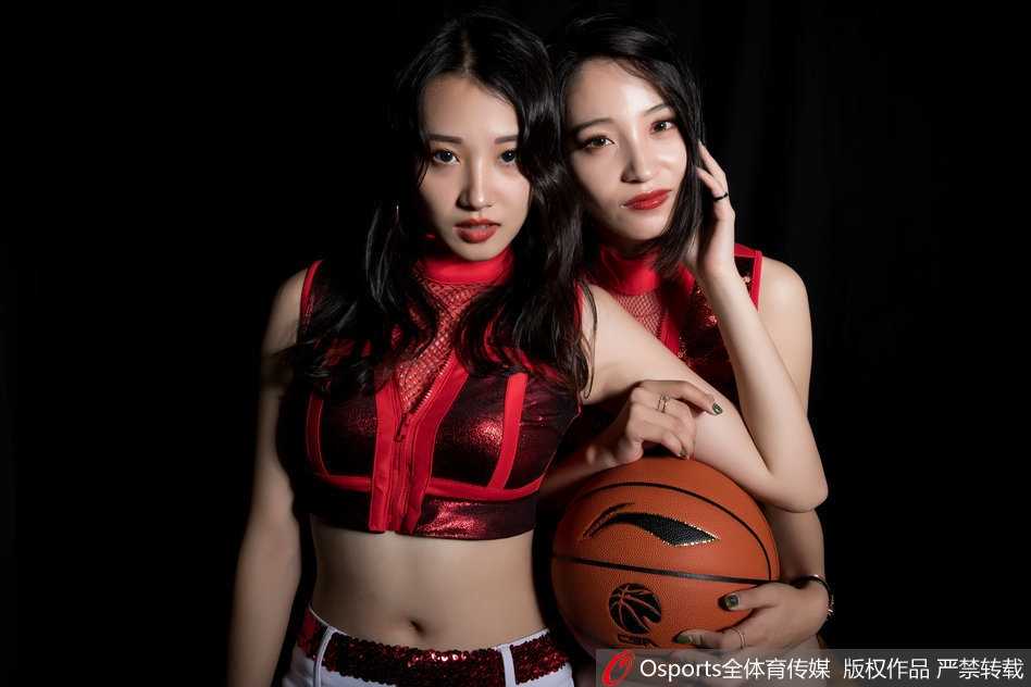 江苏肯帝亚宝贝身着一袭黑色亮片舞衣，在昏暗的聚光灯下回眸，眼神中透出坚定与神秘的魅力，仿佛暗夜中的闪耀星辰