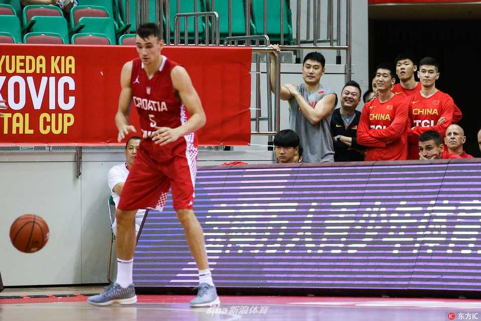 镜头拉近，中国男篮的一位球员眼神专注，嘴唇微张，似乎完全沉浸在了比赛的节奏里。背景是模糊的看台观众，他的脸上还带着些许属于年轻人的稚气，但在那一刻的凝视中，透露出的是超越年龄的沉稳。仿佛正在心中默默模拟，如果换做是自己，该如何应对眼前这激烈的欧洲对抗。