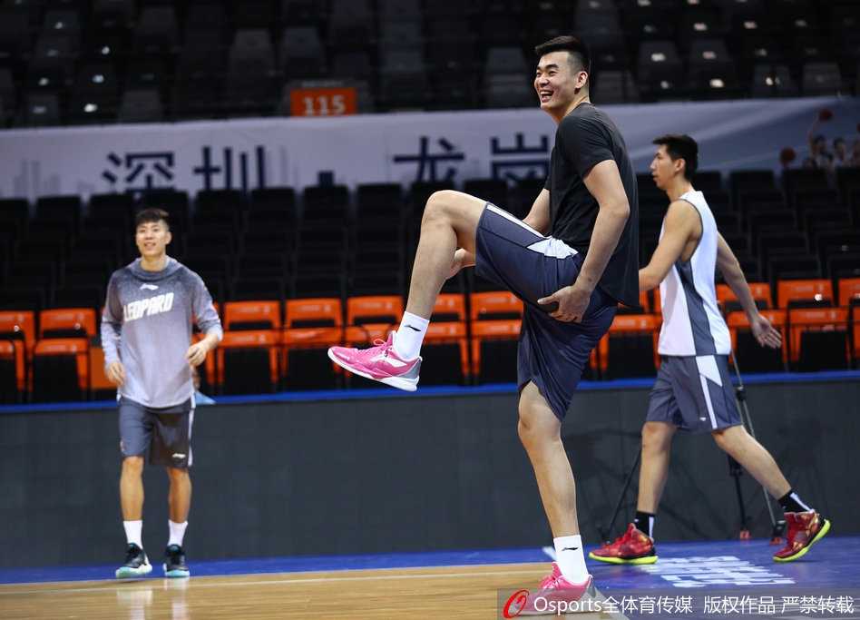 深圳队中锋李慕豪在训练中双手抱头，表情夸张地仰天大笑，他张大的嘴巴和眯成一条缝的眼睛极具感染力，身旁的队友也被这一幕逗乐，侧身看向他，整个训练馆充满了欢乐的气氛。