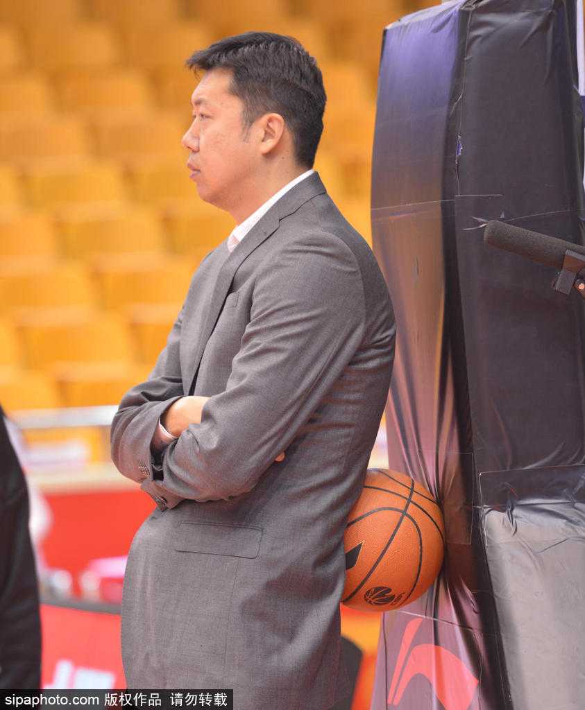 王治郅近距离观看球员热身，他高大的身影在人群中格外显眼，身旁的球员正在进行上篮练习，大郅的目光紧紧跟随篮球的轨迹。