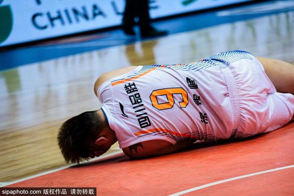 队医单膝跪地，紧急检查徐煜峰的伤情，徐煜峰的表情依然痛苦，手掌遮挡着面部，汗水似乎已经浸湿了球衣。