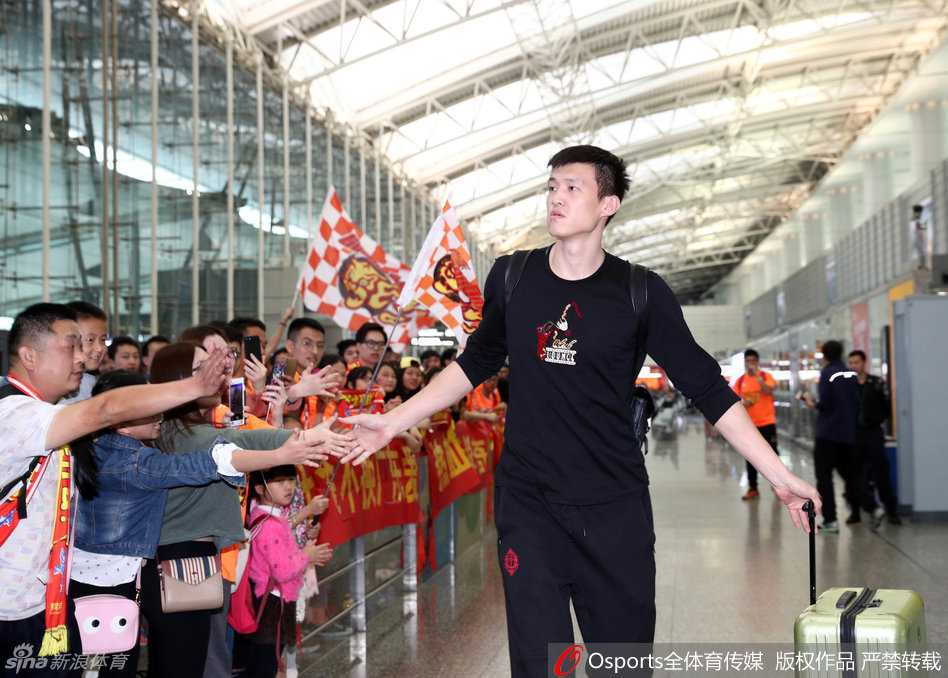 朱芳雨微微皱眉，用手擦拭着额头的汗水，身边是依然热情不减的球迷，身后的背景是机场的到达出口。
