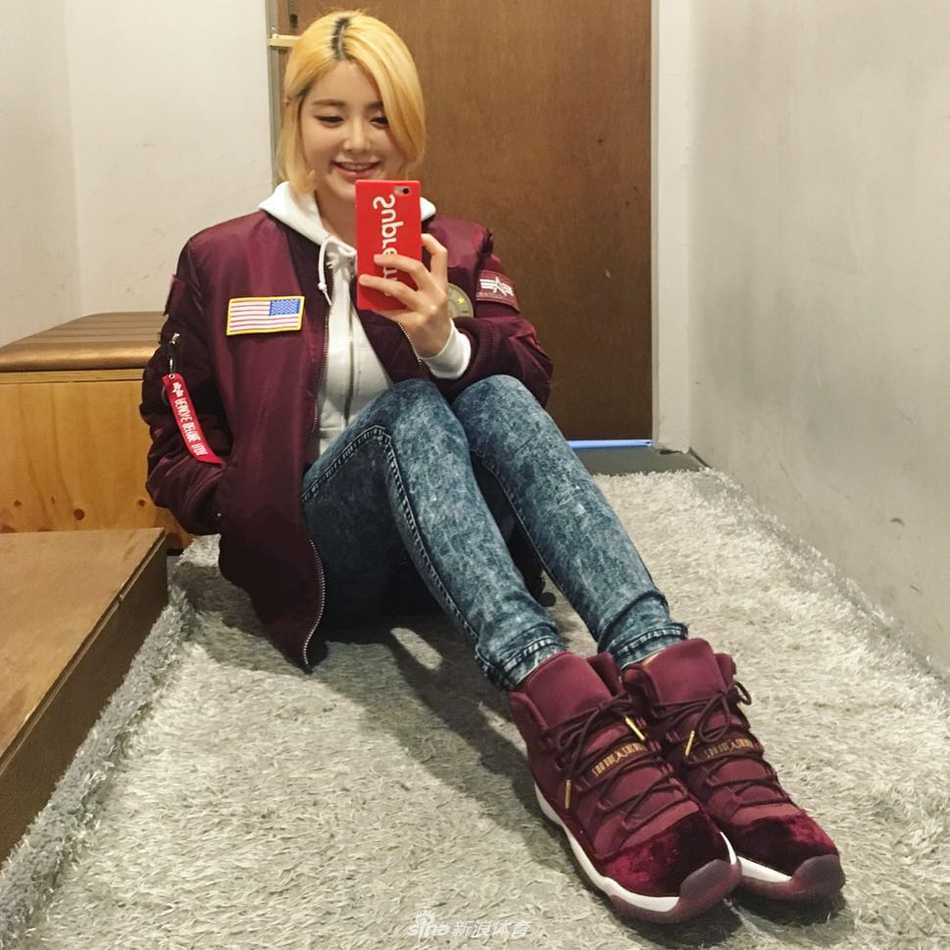 阳光洒在她精致的侧脸上，Soda正在专注地审视着什么，也许是新到的一双限量AJ？简约的白色上衣与脚下的球鞋形成鲜明对比，将她那种既清纯又带着一丝酷劲的独特气质展现得淋漓尽致。