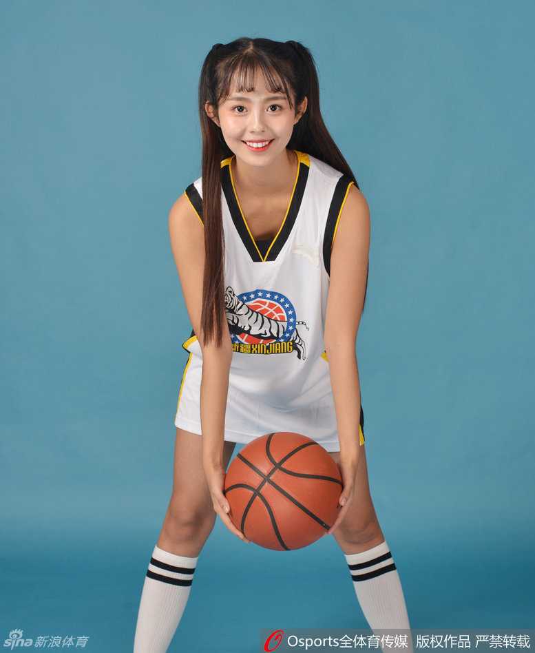 双手叉腰的宝贝展现出自信女王气场，身后的巨型飞虎队徽在灯光下与她娇俏的身影相映成辉。