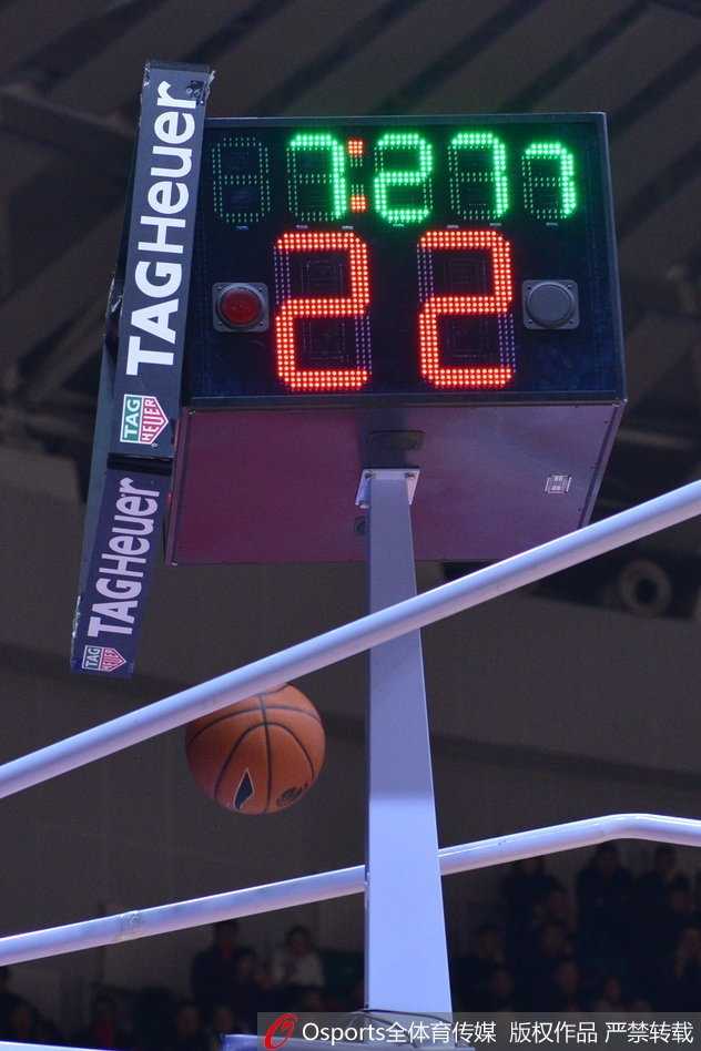 易建联在对方内线球员的包夹下强行起跳，眼神中透露出不甘与坚毅，身后的记分牌闪烁着新疆队领先的比分，记录着这位核心球员的孤独奋战