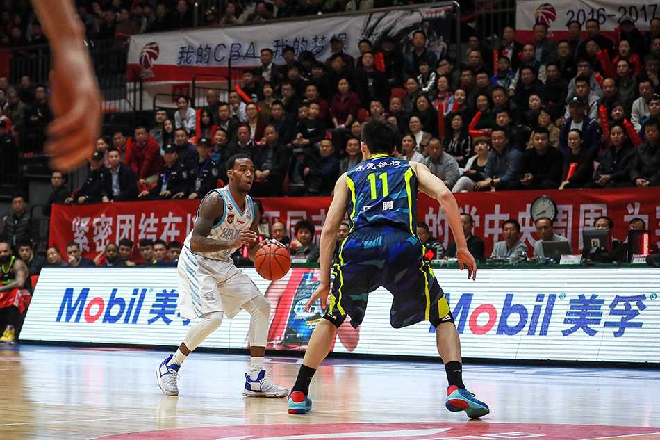 新疆队外援布拉切篮下卡位后高举双臂忘情庆祝，身后是周琦与广东队员易建联、周鹏的激烈拼抢背景