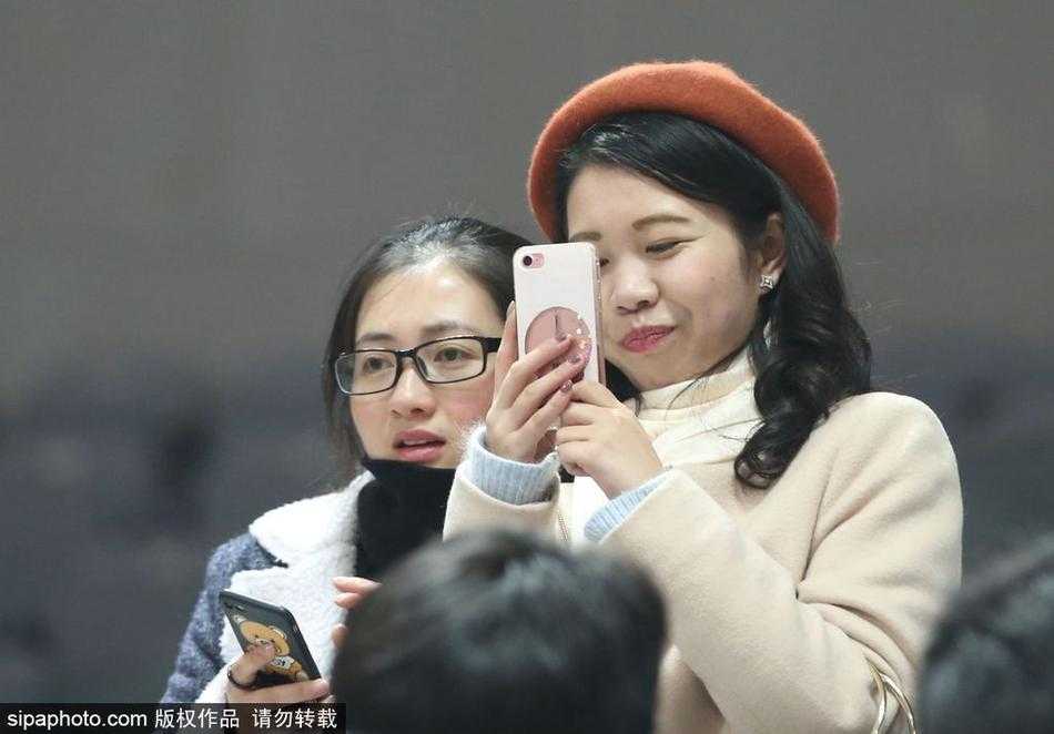 这位戴着眼镜的女球迷显得格外文静，她安静地坐在座位上，手里的手机镜头却早已对准了球场方向，或许是想记录下偶像赛前训练的珍贵瞬间，那份专注让人不忍打扰。