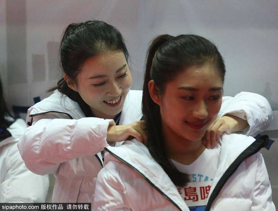 球场灯光下，一位戴着眼镜的女生正在专注地查看手机，背后是正在热身的大个子球员们。她或许是正在给无法到场的朋友发去现场的照片，分享着这份属于宁波冬夜的篮球热情。