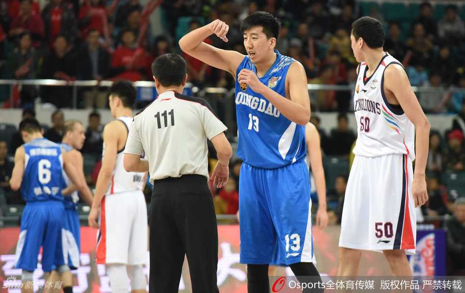 裁判员站在技术台前认真观看录像回放，场边教练组焦急等待，身后是黑压压的观众席