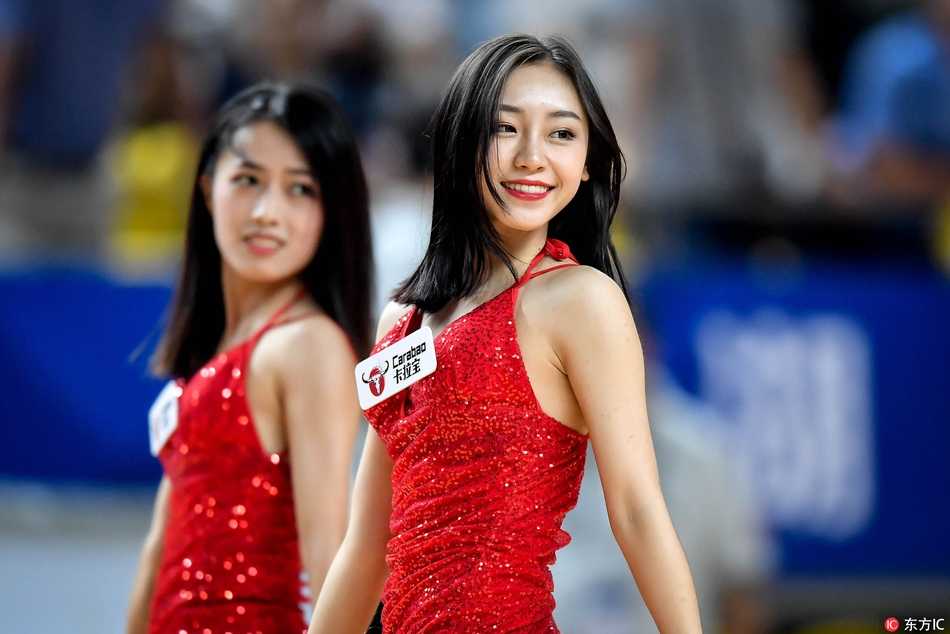 灯光下，一名啦啦宝贝的侧脸轮廓精致而专注，她手中的花球随着动感节奏幻化成一片绚烂的光影，为激烈的比赛间隙带来了一抹灵动的艺术气息。