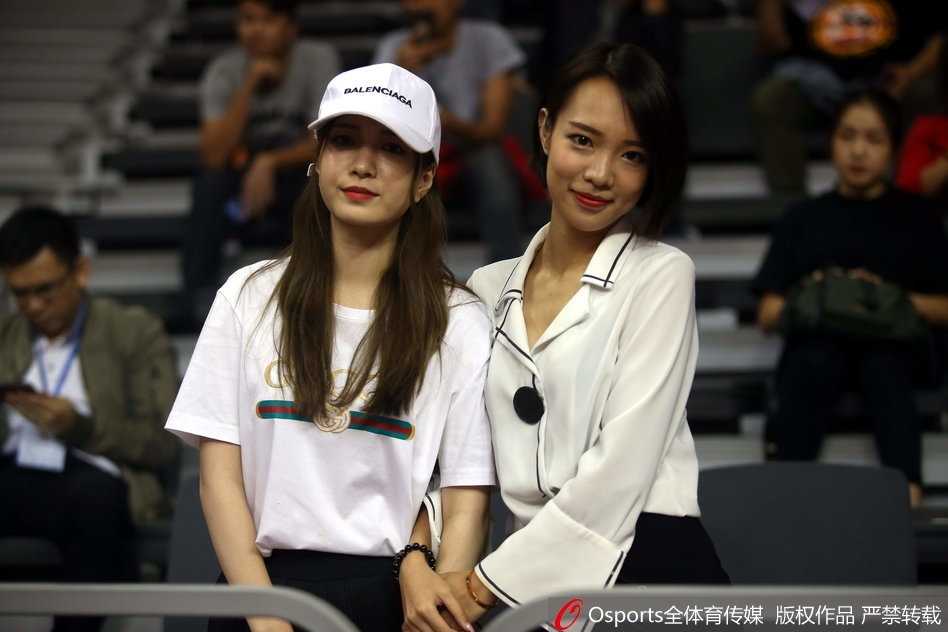 一位身穿浅色外套的女球迷，在人群中安静地注视着球场，眼神清澈，成为激烈赛事旁一道温婉的风景线。