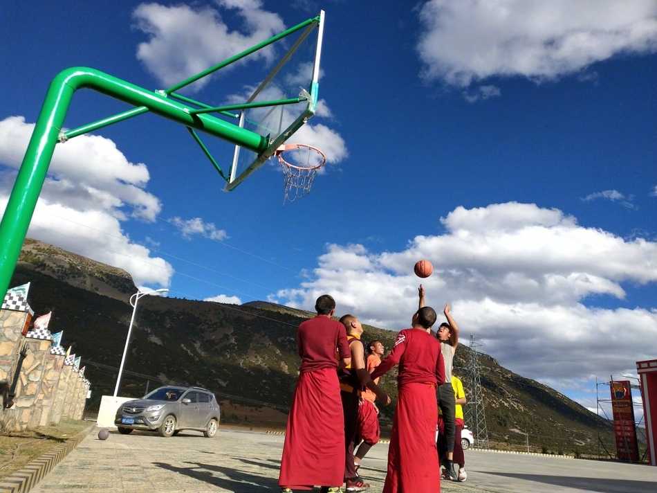 球场上，两名喇嘛正激烈地争抢篮板，僧袍的宽大袖口随风扬起，露出他们结实的手臂。他们的眼神紧盯着篮球，那股认真劲儿丝毫不亚于专业运动员。